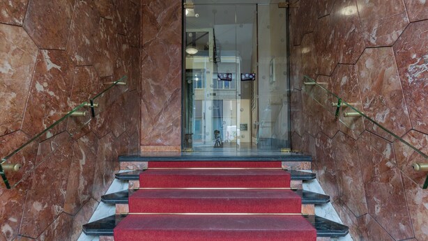 A marble staircase with red carpeted steps leading to a glass door. - CasaTo by Wonderful Italy (Turin)