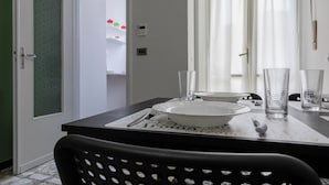 A dining area with a table set for two, a white plate, two clear glasses, and a black chair. - CasaTo by Wonderful Italy (Turin)