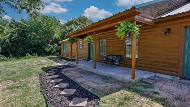Une cabane en bois dotée d’une véranda, d’un banc et d’un chemin menant à l’entrée.