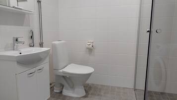 Et moderne badeværelse med en hvid vask, toilet og brusebad.