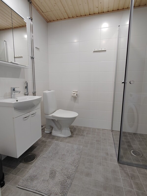 A modern bathroom with a white sink, toilet, and shower. - Forenom Serviced Apartments Oulu Lekatie (Oulu)