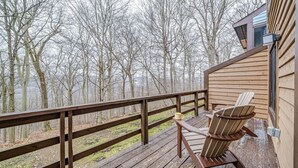A wooden deck with a railing, a chair, and a table. - 3 Bed, 2 Bath in Seven Springs Resort (Champion)