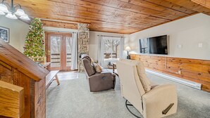 A cozy living room with a stone fireplace, a reclining chair, a Christmas tree, and a large TV. - 3 Bed, 2 Bath in Seven Springs Resort (Champion)