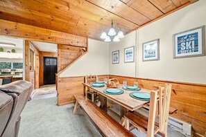 Ein Holzespeisesaal mit Bänken, einer Chandelüster und gerahmten Bildern an der Wand.