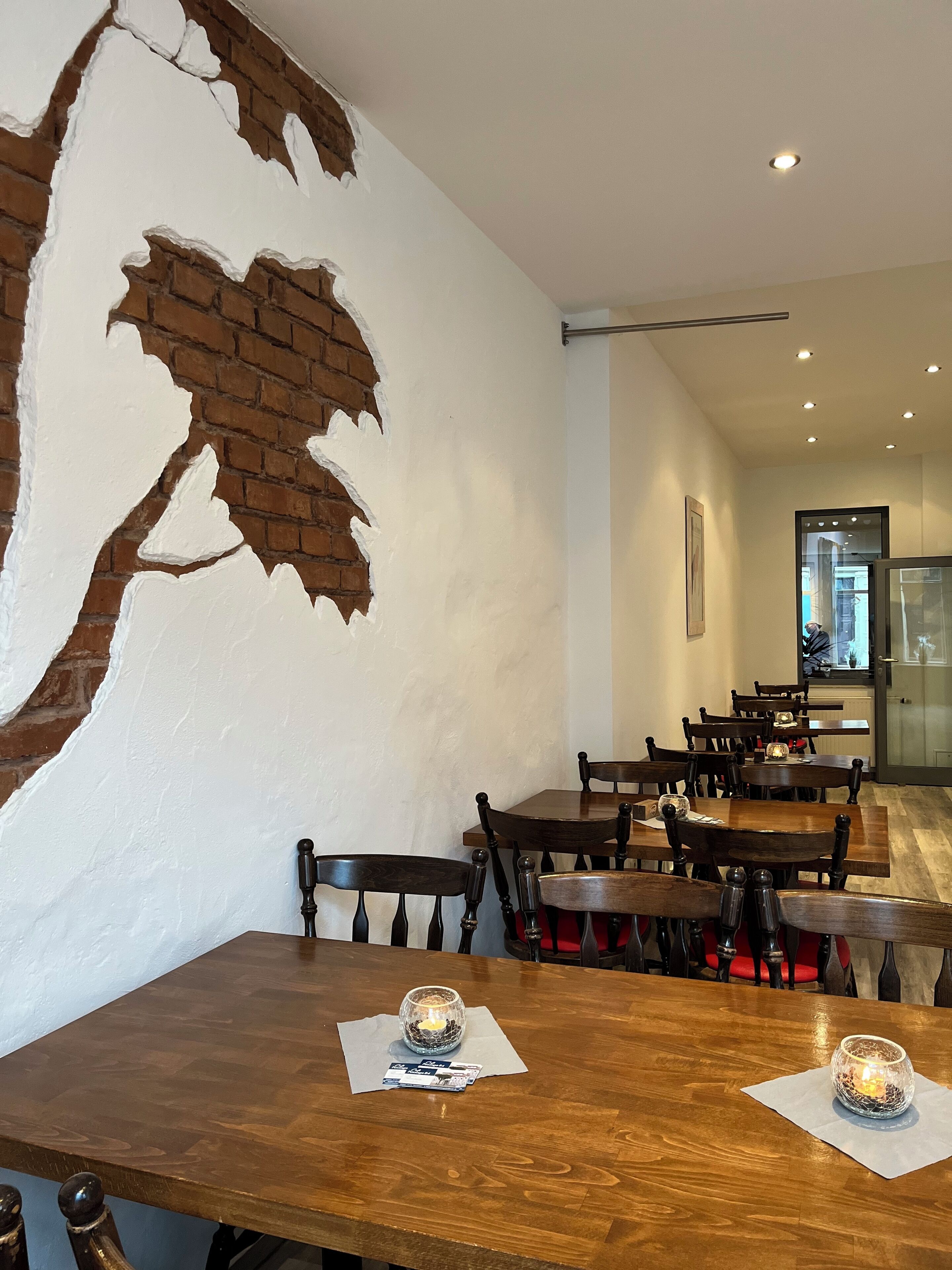 A restaurant interior with brick walls, wooden tables, and chairs.
