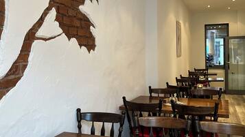 A restaurant interior with brick walls, wooden tables, and chairs.