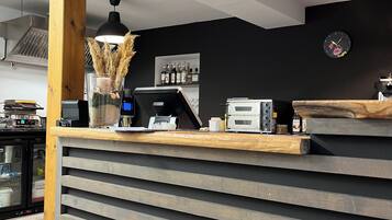 A modern reception desk with a wooden finish, a black wall clock, and a coffee machine.
