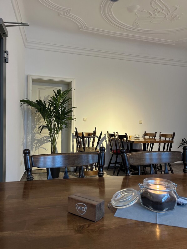 A dining area with wooden furniture, a potted plant, and a candle on the table.
