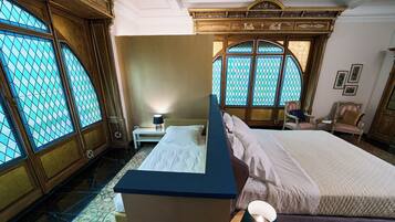 Une chambre à coucher avec un grand lit, une table de chevet, une commode et une fenêtre ornée de vitraux.