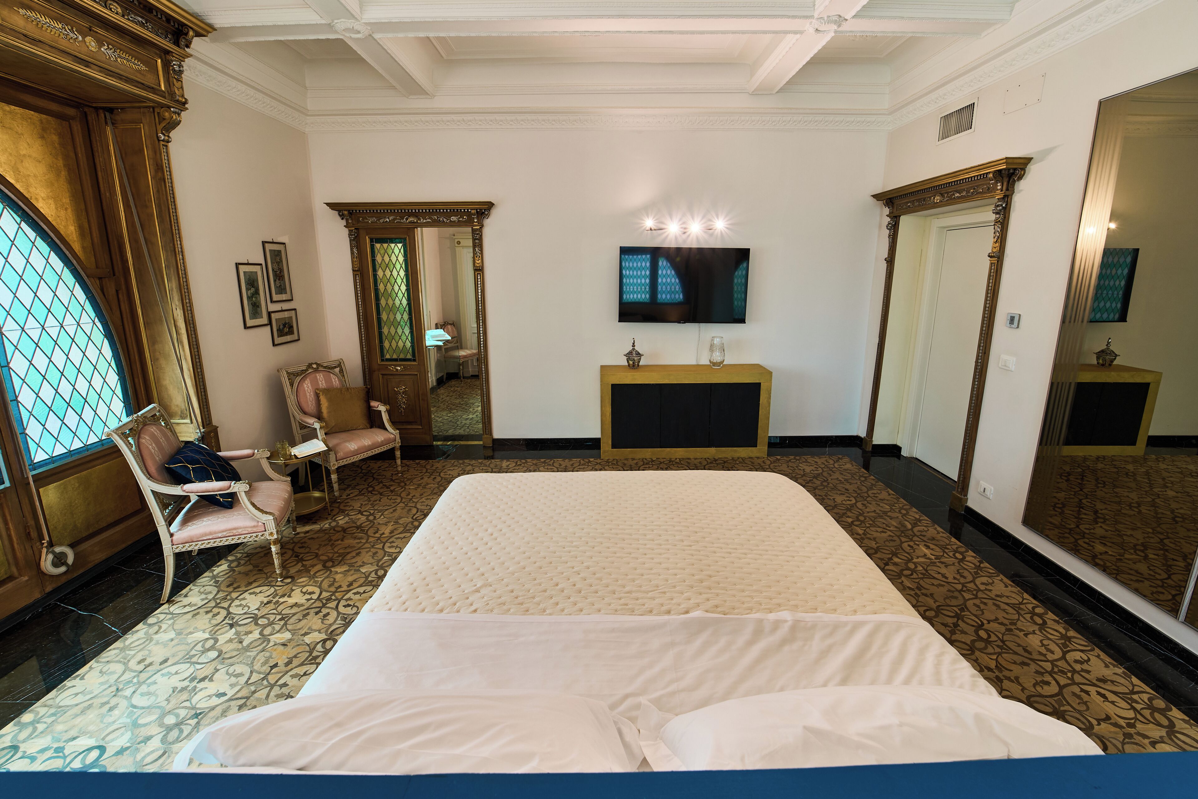 Une chambre spacieuse avec un grand lit, une télévision et un miroir.