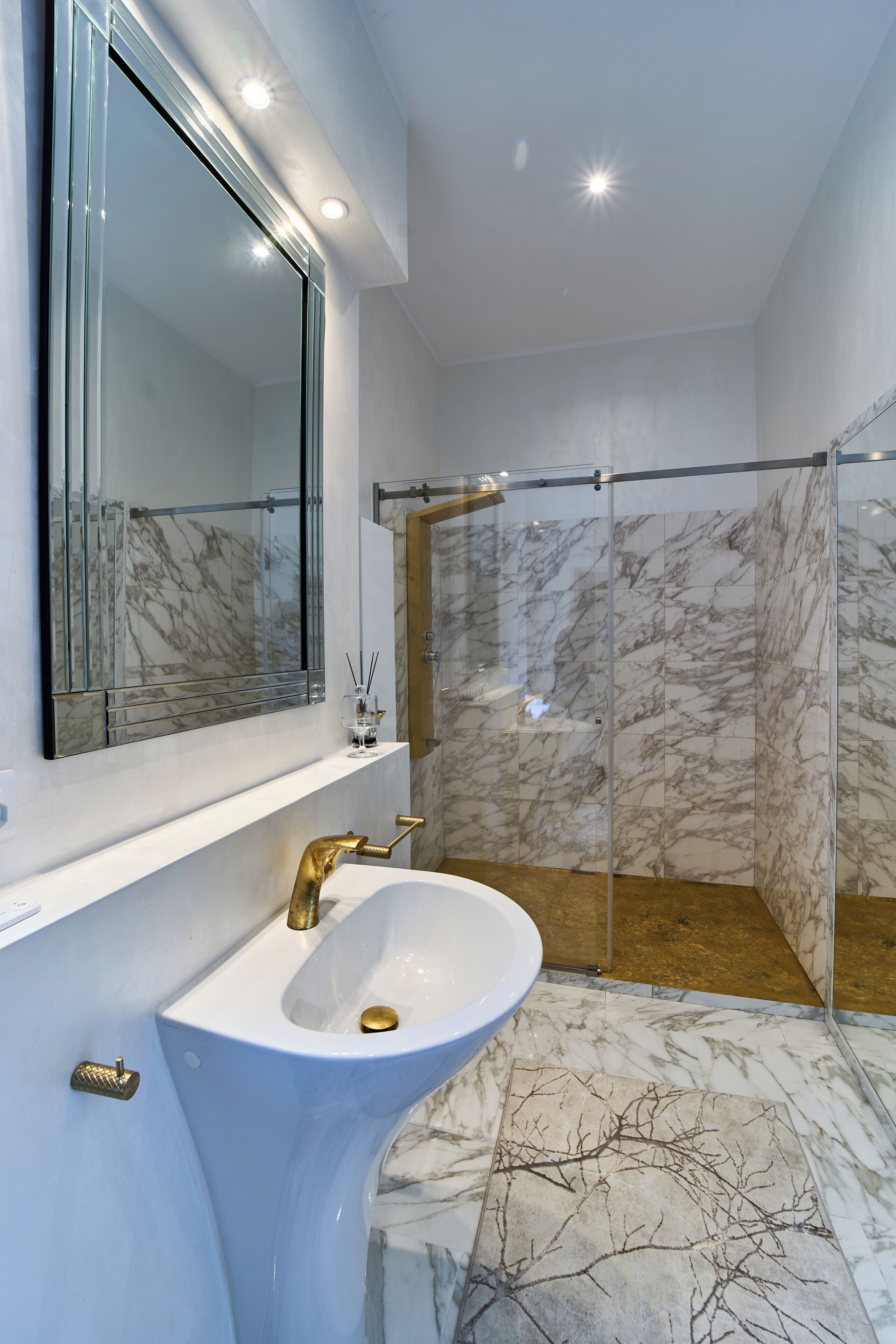 A bathroom with a marble sink, a large mirror, and a glass-enclosed shower.