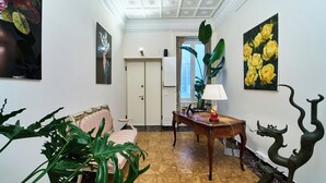 A hallway with a patterned floor, a sofa, a table with a lamp, and a decorative dragon sculpture. - GLAM TIME (Genoa)