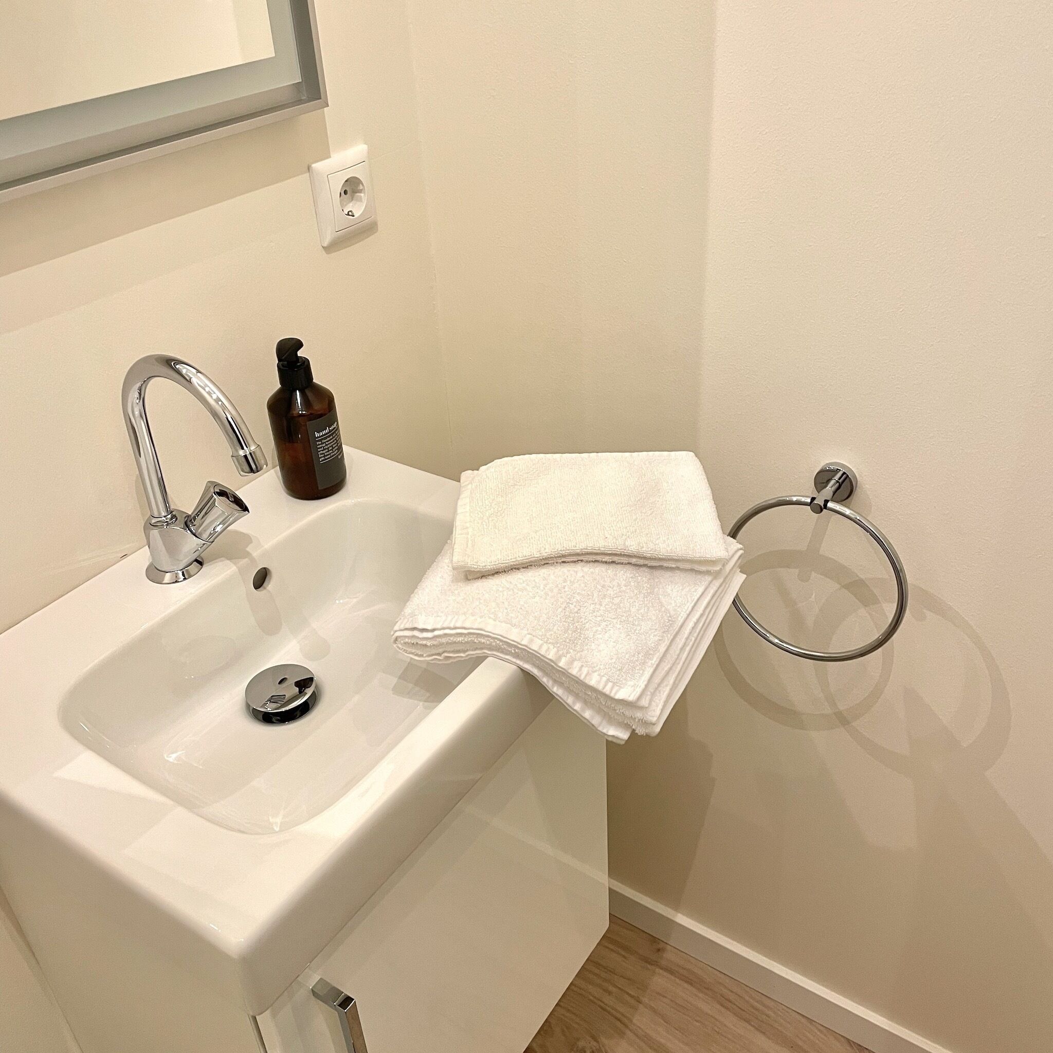 A bathroom with a white sink, a hand soap dispenser, and a towel rack.