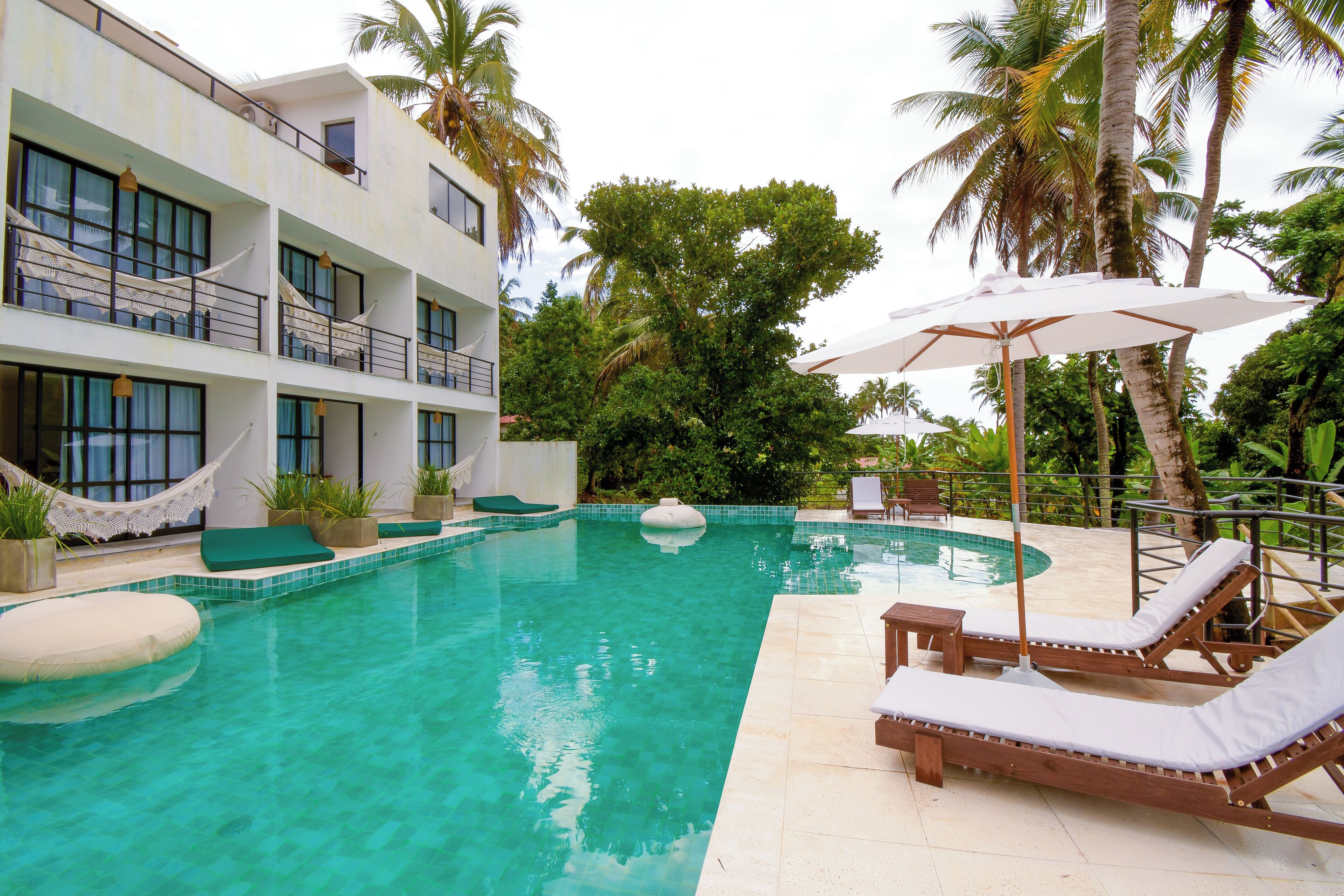 A pool area with lounge chairs and a hammock.