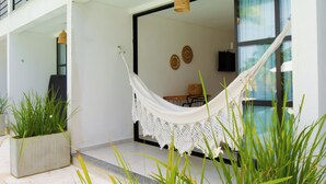 A hammock in a modern outdoor space with a view of a pool and a dining area. - Milie Lounge Pousada (Japaratinga)