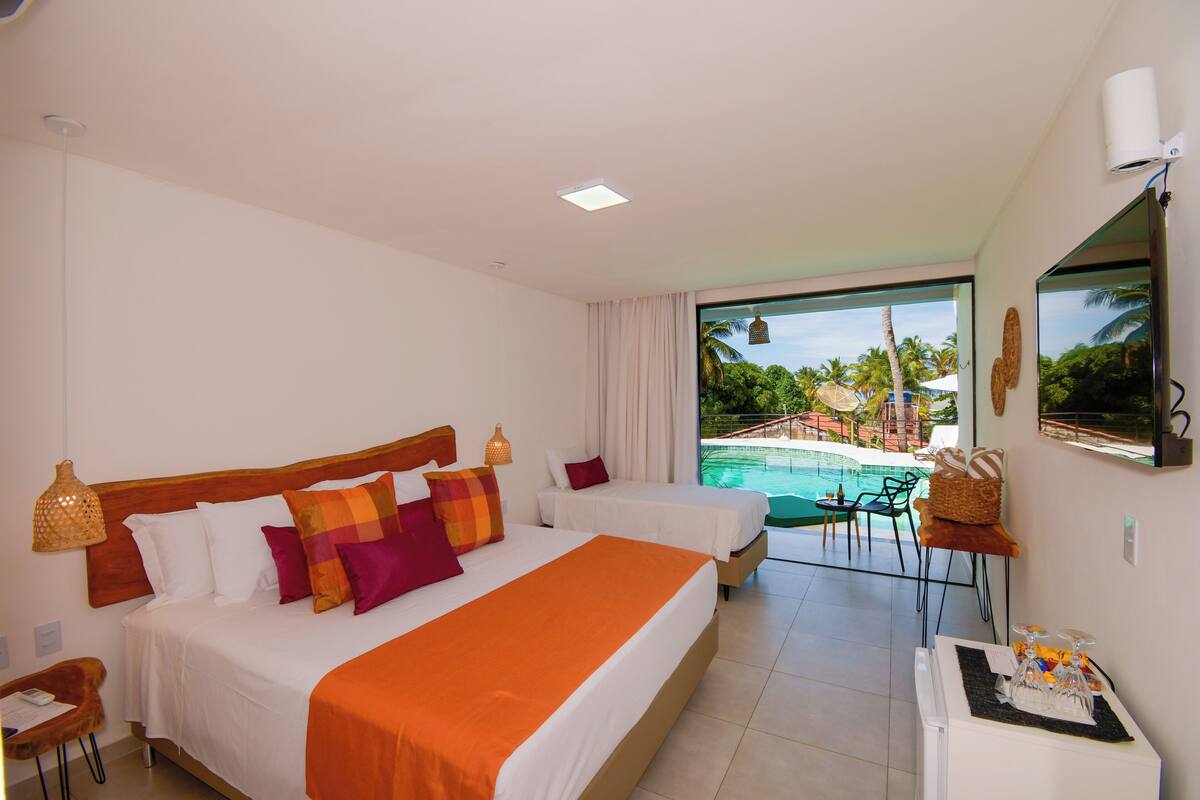 Habitación de hotel con dos camas, vista a una piscina y zona de comedor.