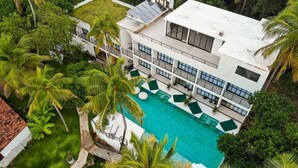 A modern hotel with a swimming pool surrounded by palm trees. - Milie Lounge Pousada (Japaratinga)