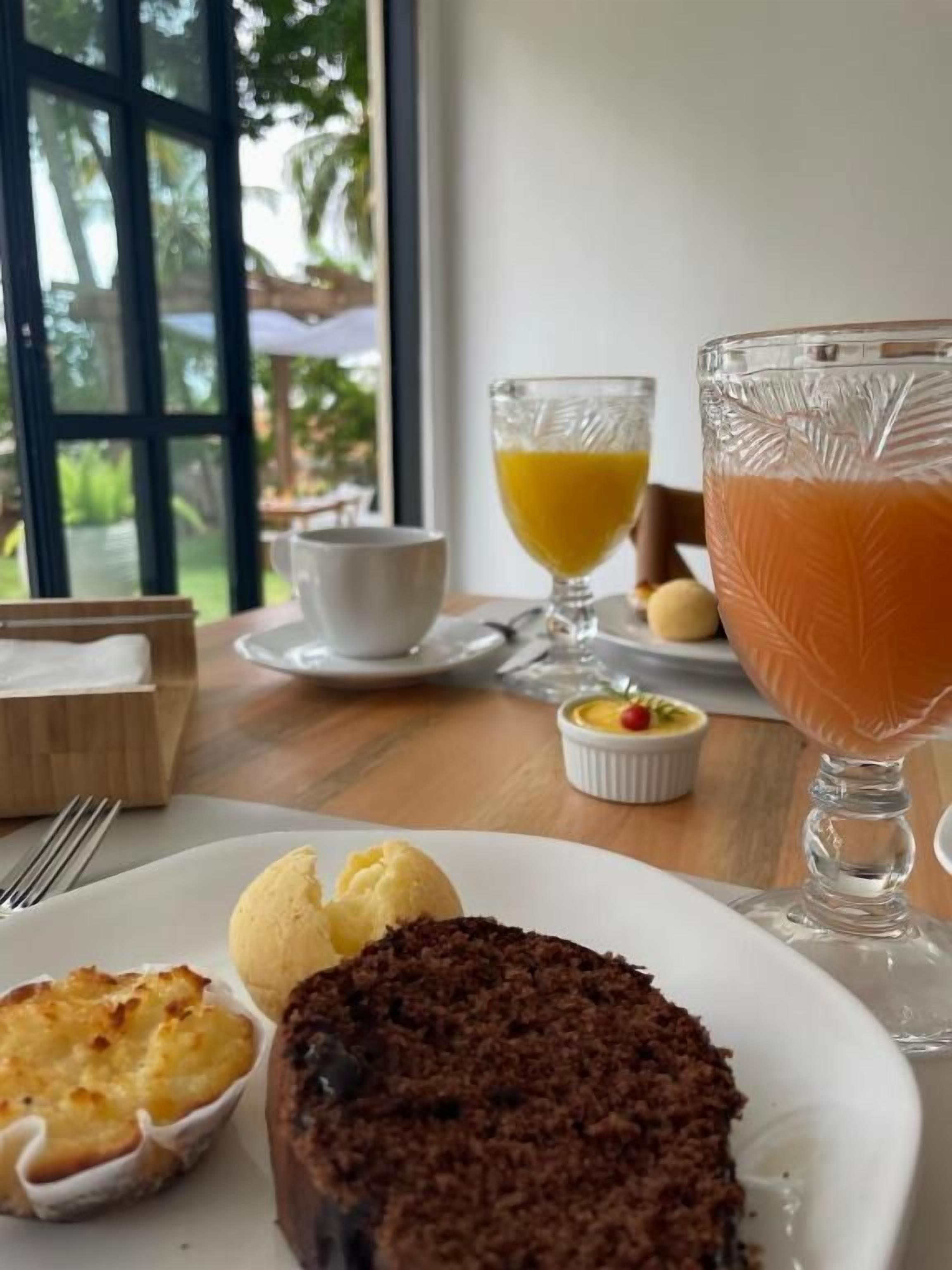 A dining table with a plate of food, a glass of orange juice, and a dessert.