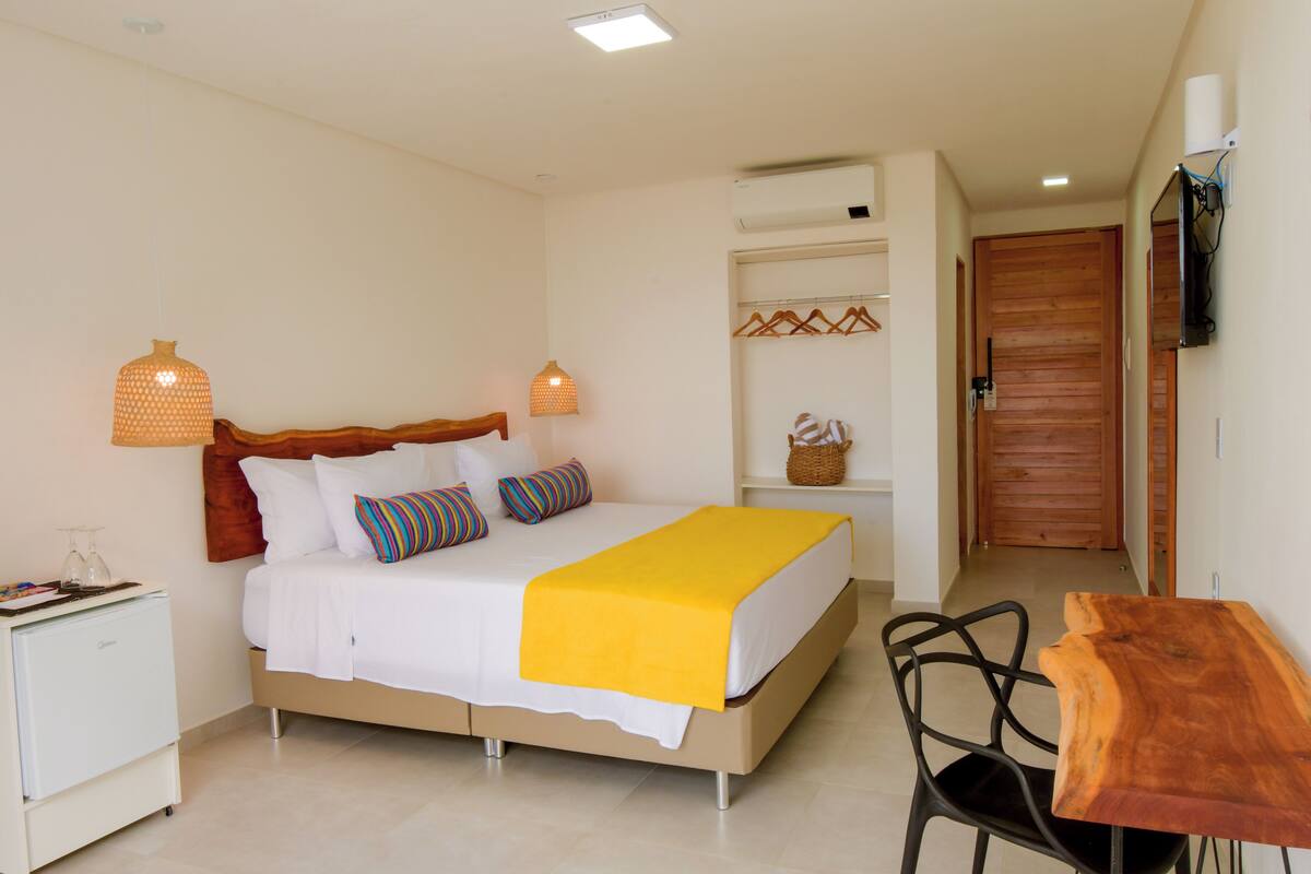 Un dormitorio con cama, mesitas de noche, un escritorio y una silla.