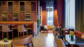 A modern interior with a seating area featuring leather sofas and chairs, a dining table, and a decorative wall with geometric patterns. - Caption by Hyatt Downtown Nashville (Nashville)