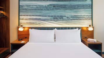 Une chambre d’hôtel avec un grand lit, deux tables de chevet, une tête de lit en bois et une œuvre d’art murale.