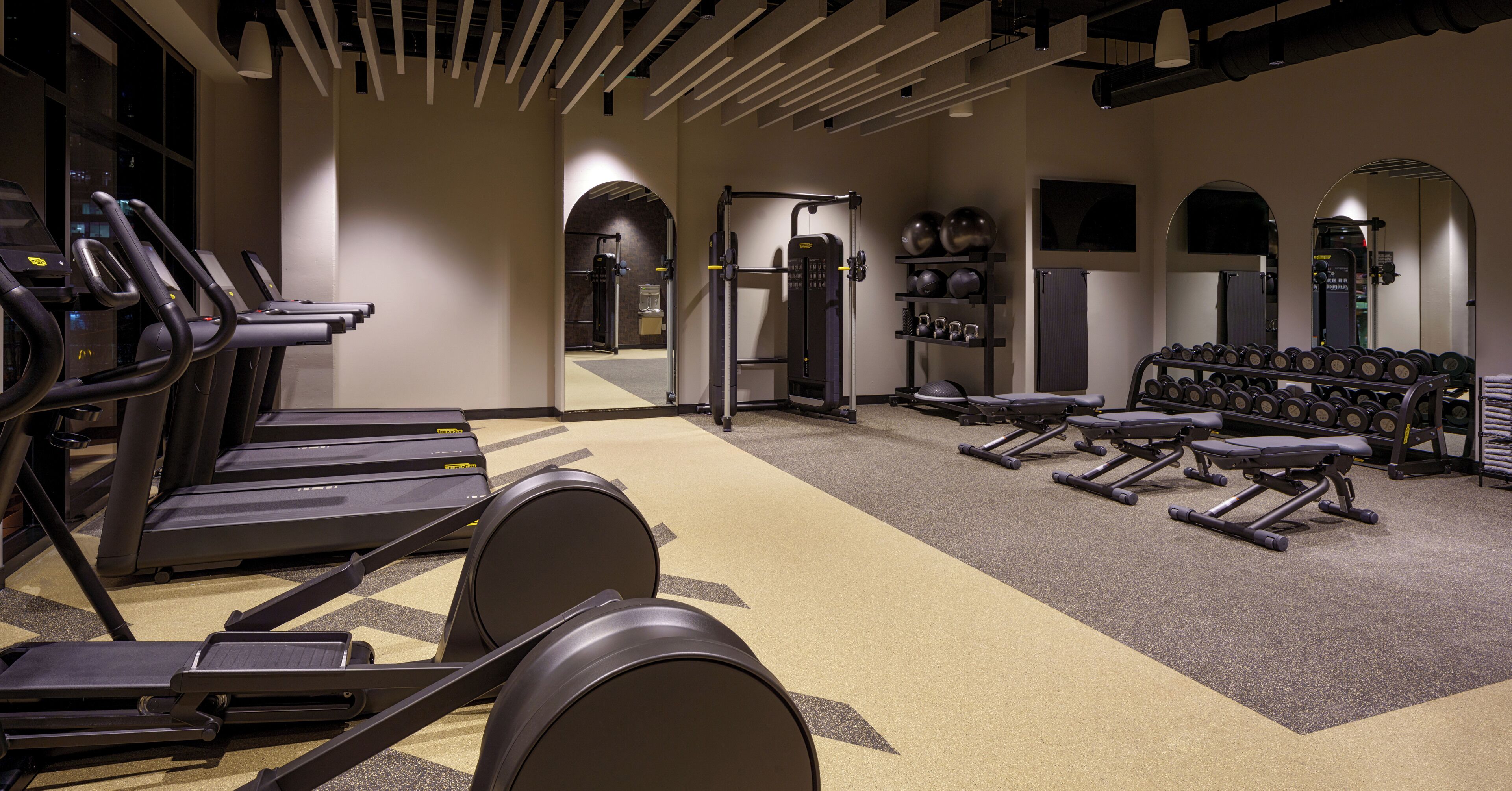 A gym with treadmills, weight benches, and dumbbells.