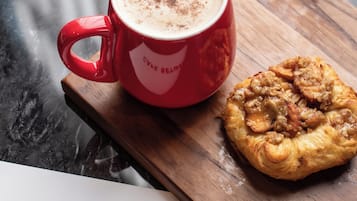 Una taza roja con una bebida espumosa y un pastel sobre una tabla de madera.