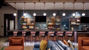 A bar area with a counter, bar stools, and shelves stocked with bottles. - Caption by Hyatt Downtown Nashville (Nashville)