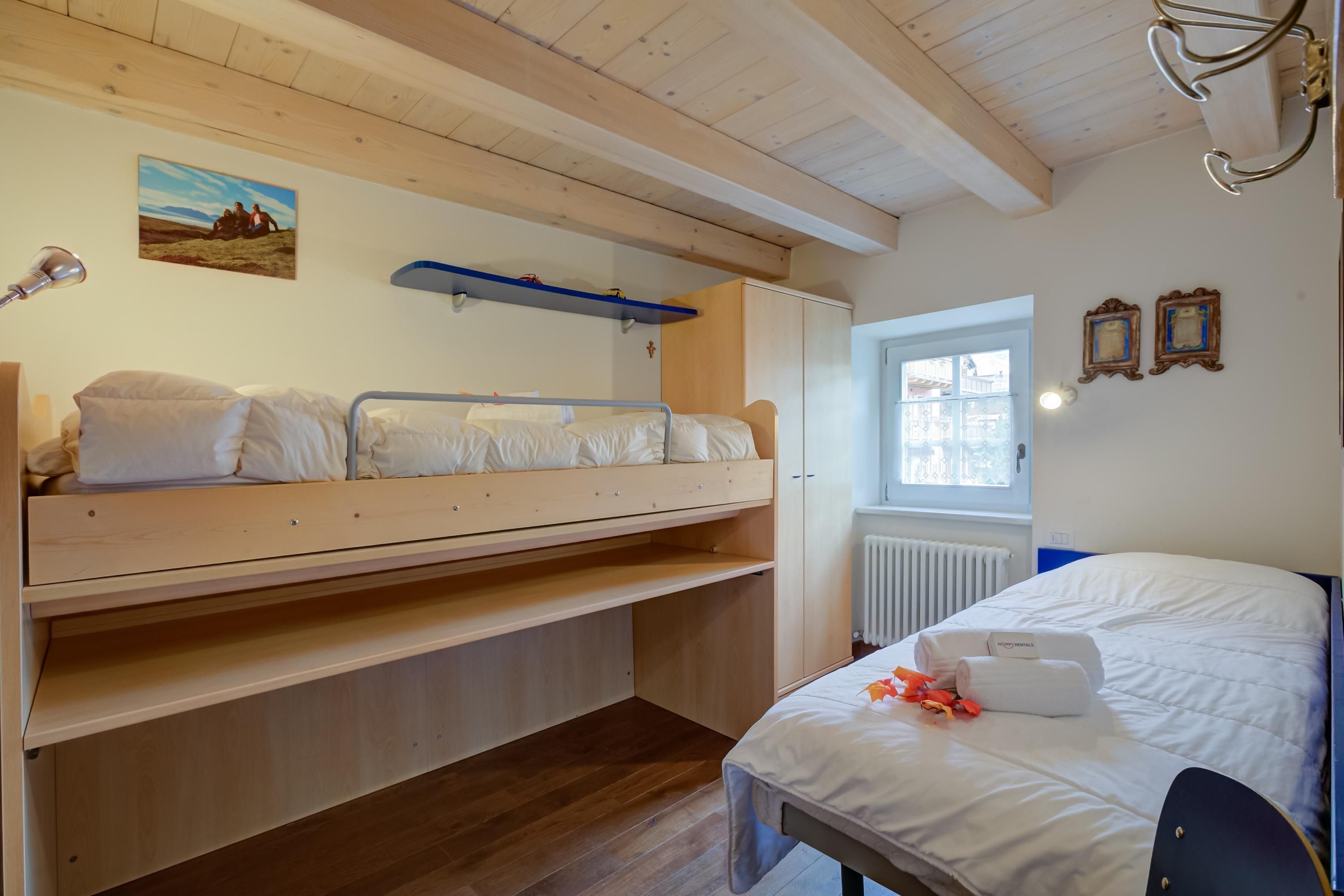A room with a bunk bed, a desk, a radiator, and a window.