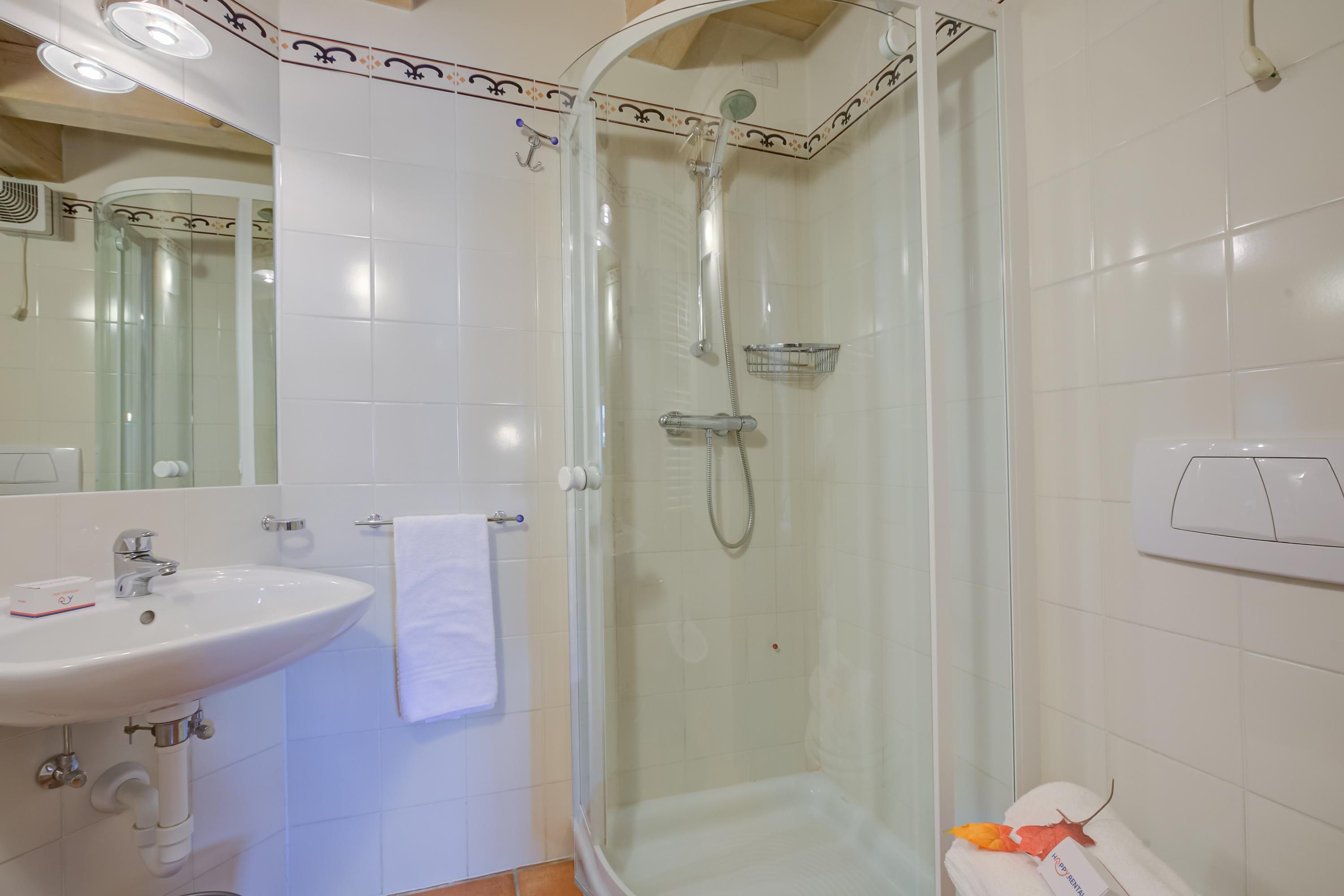 A bathroom with a glass-enclosed shower, a white sink, and a mirror.