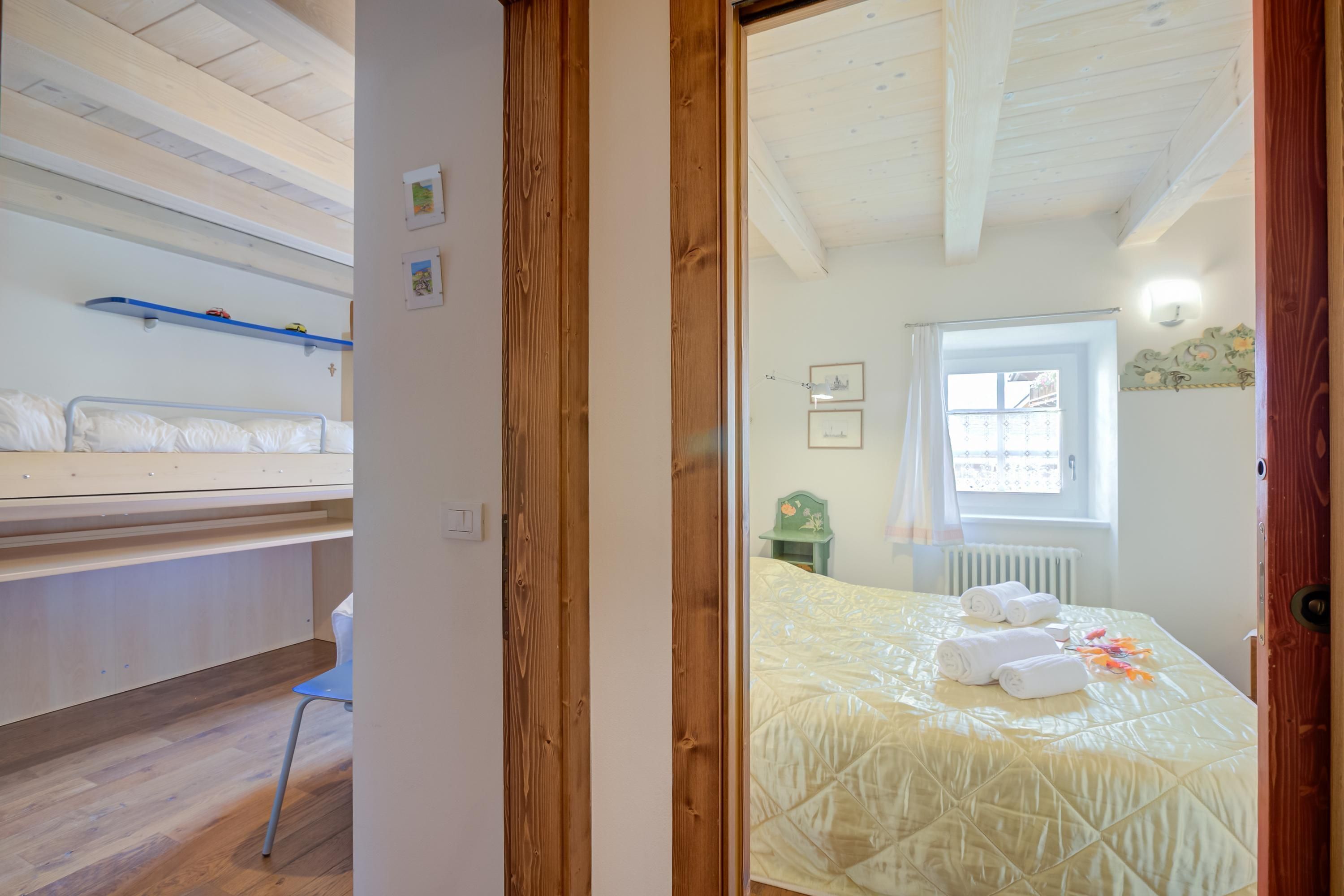 Une pièce avec un lit, une chaise, un plafond en bois et une fenêtre.