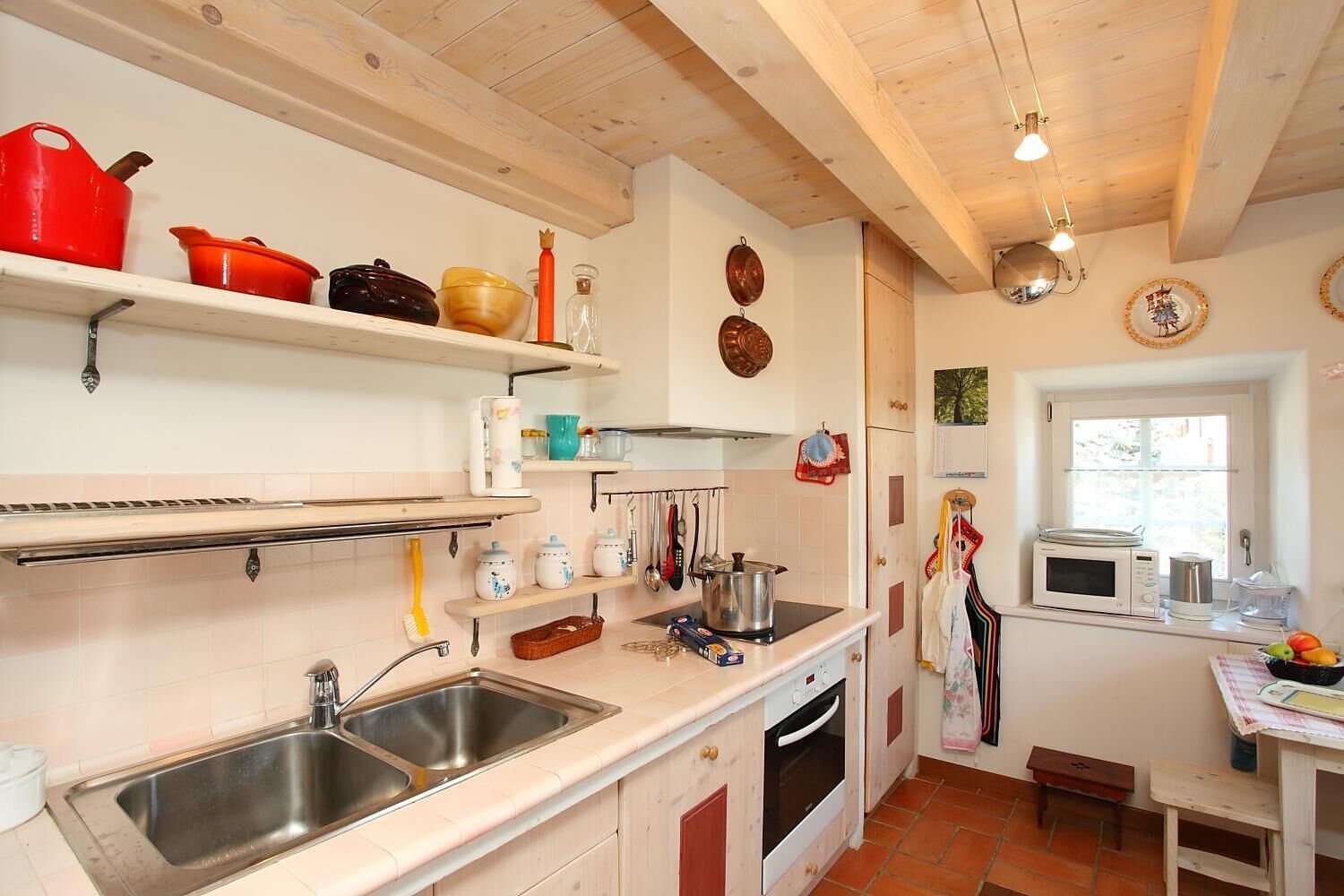 A kitchen with wooden cabinets, a stainless steel sink, and a window with a view of greenery.