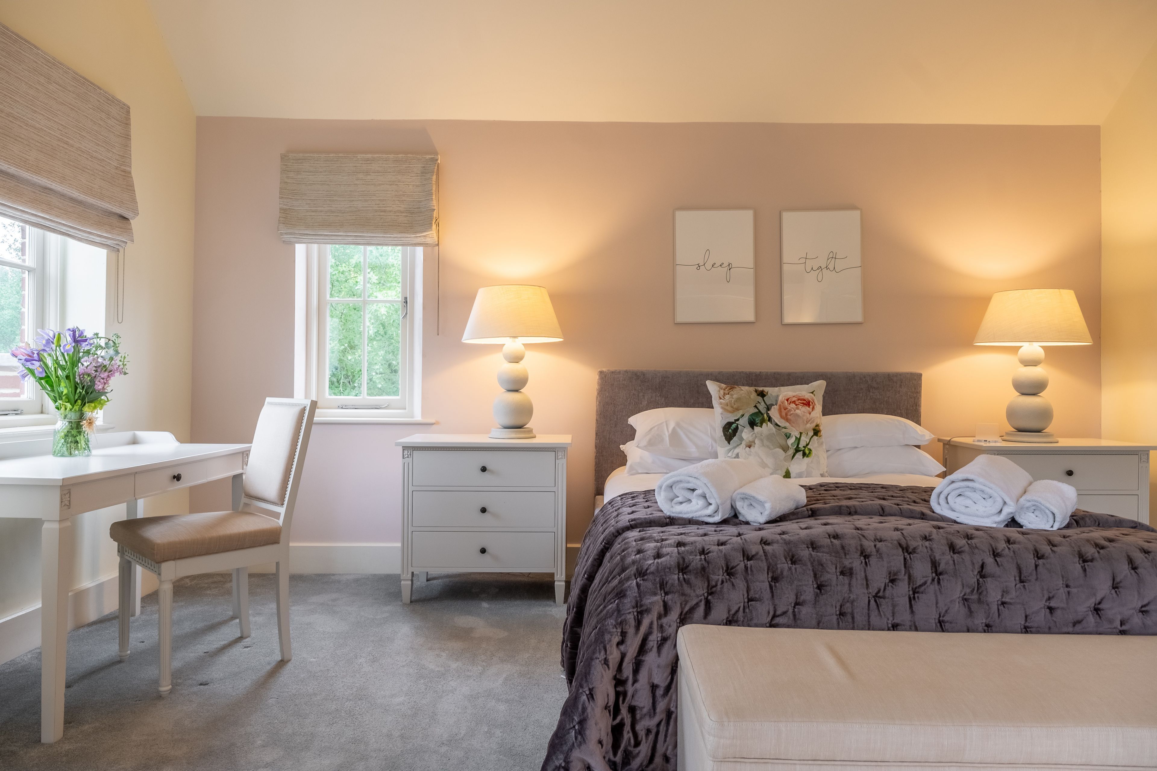 A bedroom with a bed, bedside tables, a desk, and a chair.