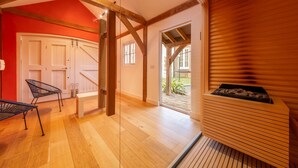 A room with wooden beams, a bench, a fireplace, and a door leading to a garden. - Seagate House, Brancaster, Norfolk (Brancaster)