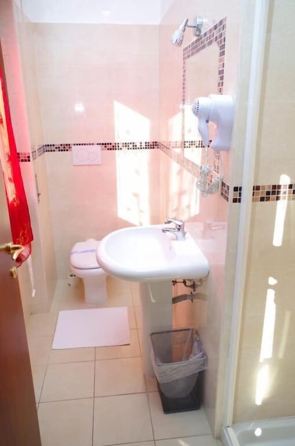 A bathroom with a toilet, sink, and shower area. - Hotel Centrale (Milan)