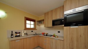 Una cocina moderna con armarios de madera, un microondas Bosch y una ventana con cortinas rojas.