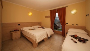 A hotel room with two beds, a wooden headboard, a nightstand, a window with curtains, and a balcony view. - Sponda Ski in- Ski out Mt 50 (Livigno)