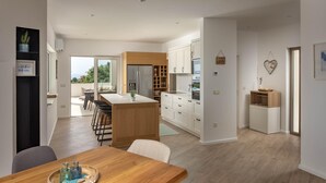 Een moderne keuken met witte kasten, een houten eiland en een eethoek met een houten tafel.