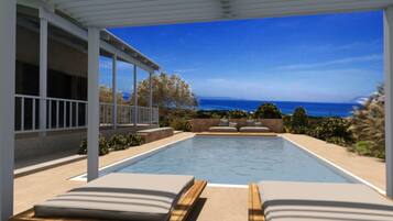 An infinity pool with two lounge chairs, a pergola, and a view of the ocean.