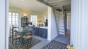 A spacious living area with a dining table, chairs, a bookshelf, and a ladder leading to an upper level. - Villa Filokalia With Exceptional View (Andravida-Kyllini)