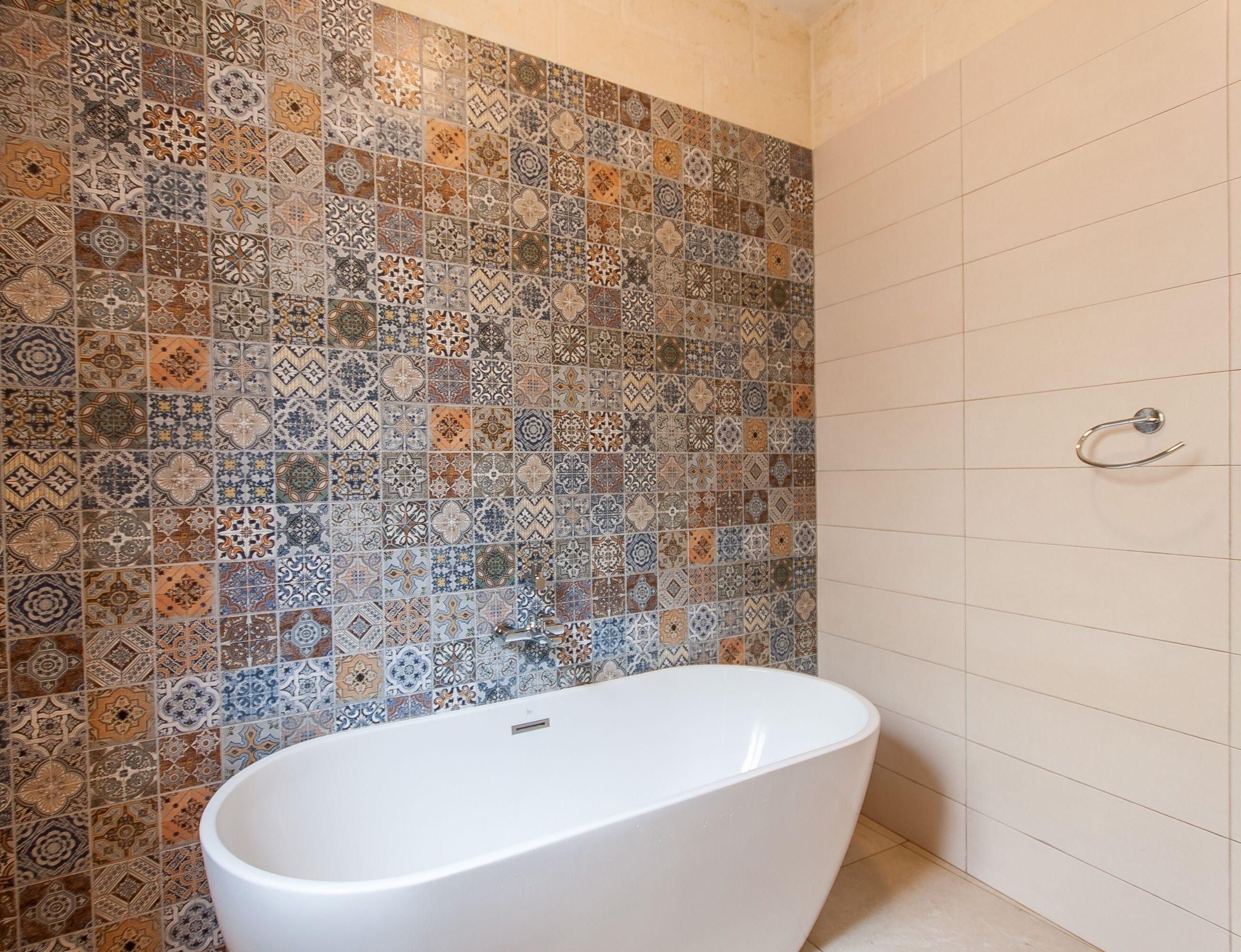 Une salle de bain avec une baignoire sur pieds, un mur de douche carrelé et un porte-serviettes.