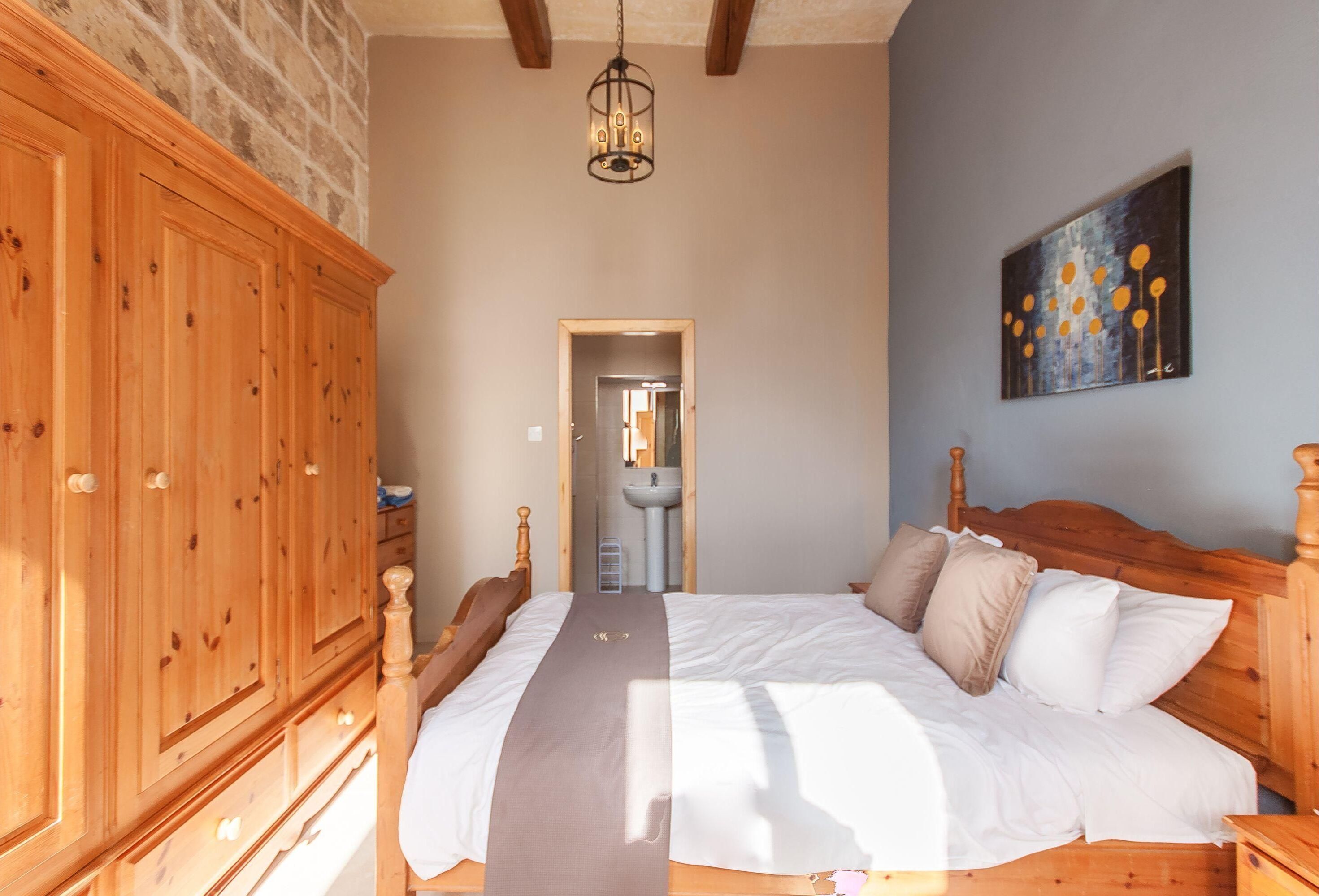 A bedroom with a wooden bed, a large wardrobe, and a painting on the wall.