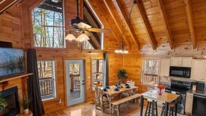 A spacious wooden cabin interior with a dining area, kitchen, and a fireplace. - Spectacular Secluded Fire Pit Arcade Jacuzzi (Sevierville)