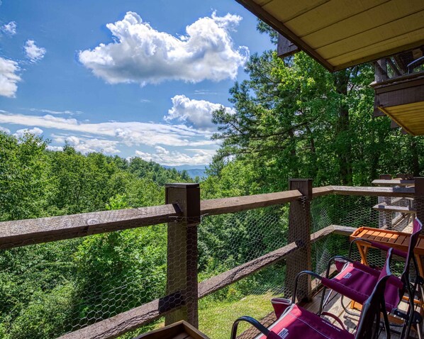 A wooden deck with a metal fence overlooking a forested area with mountains in the distance. - Newly Renovated 5 Star Condo Pool Gorgeous View (Sevierville)