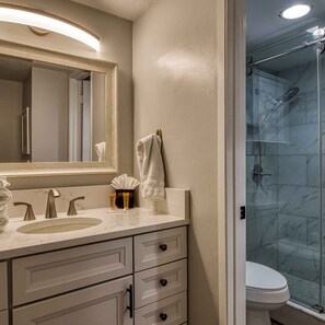 A bathroom with a large mirror, two sinks, a shower, and a toilet. - Newly Renovated 5 Star Condo Pool Gorgeous View (Sevierville)