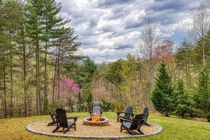 A circular outdoor seating area with a fire pit, surrounded by a grassy field and trees. - Fantastic Pet Friendly Cabin Hot Tub Fire Pit (Sevierville)