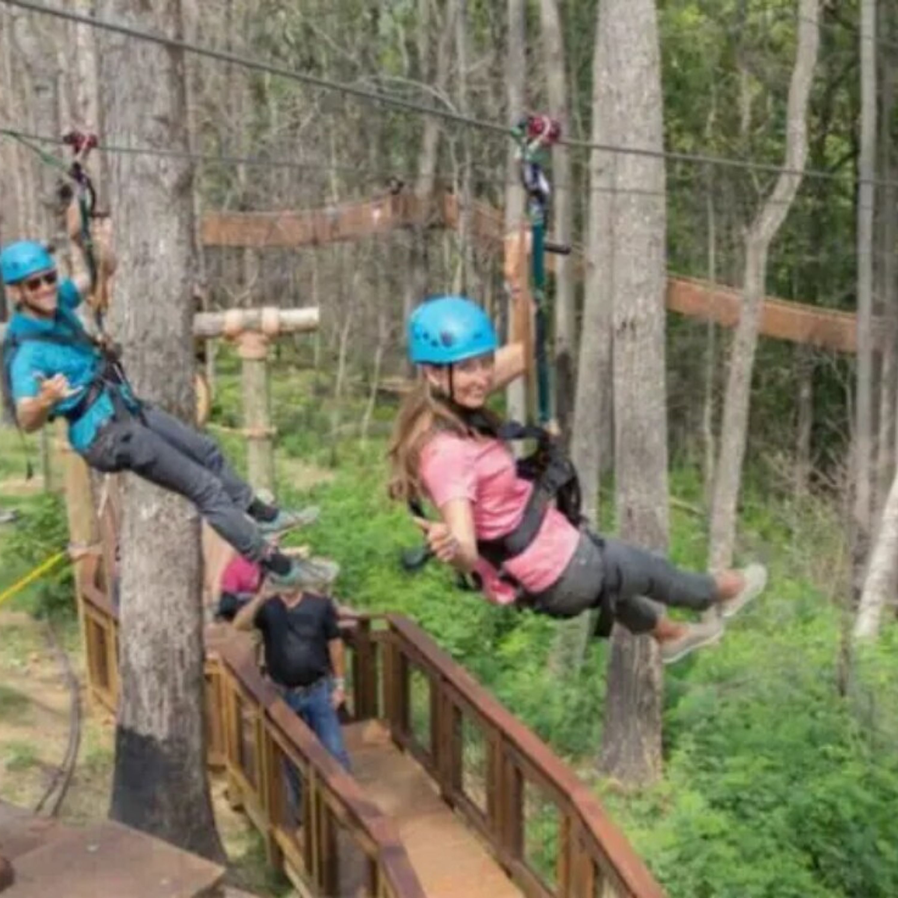 A zip-lining course with participants in safety gear.