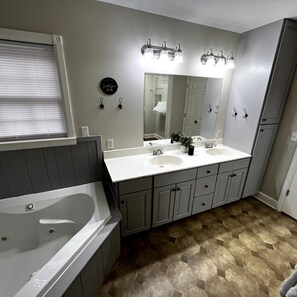 Ein Badezimmer mit einem Doppelwaschbecken, einem großen Spiegel und einer Badewanne.