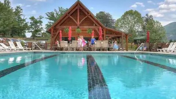 A swimming pool with a wooden pavilion in the background. - Pet Friendly Fire Pit Movie Theater Pool Sauna (Sevierville)