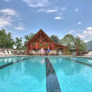 Una piscina con un padiglione in legno sullo sfondo.